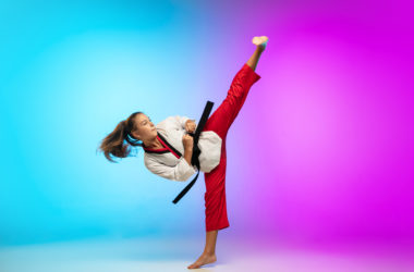 Karate, taekwondo girl with black belt isolated on gradient background in neon light
